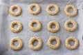 Raw rings of greek orange sesame cookies koulourakya on a parchment baking sheet before baking, top view. Step by step