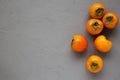 Raw Ripe Orange Persimmons on gray surface, top view. Flat lay, overhead, from above. Space for text