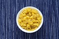 Macaroni ruote Pasta in a white cup on a striped white blue cloth background in the center. Close-up with the top. Royalty Free Stock Photo