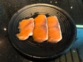 Raw salmon filet on black dish in restaurant