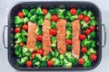 Raw salmon fillet with broccoli and tomato on frying tray, ready to bake, horizontal, top view Royalty Free Stock Photo