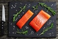 Raw salmon fillet with fresh rosemary,. salt on slate plate on old dark wooden table with knife, view from above, close-up Royalty Free Stock Photo