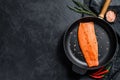 Raw salmon fillet with salt and chili pepper in a pan. Organic fish. Black background. Top view. Copy space Royalty Free Stock Photo