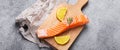 Raw salmon fish fillet with lemon wedges and rosemary on wooden cutting board Royalty Free Stock Photo