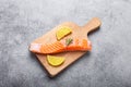 Raw salmon fish fillet with lemon wedges and rosemary on wooden cutting board Royalty Free Stock Photo