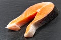 Raw salmon steak on black stone, prepared for cooking. close up Royalty Free Stock Photo