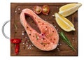 Raw salmon steak on a wooden cutting board, lemon slices, spices. Top view, white isolated background Royalty Free Stock Photo