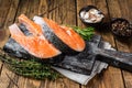 Raw Salmon steaks on a wooden cutting board with thyme and rosemary. wooden background. Top view