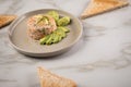Raw salmon Tatar with dill, lemon zest, cream, avocado and whole grain toast bread on porcelain plate Royalty Free Stock Photo