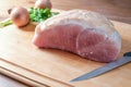 Raw salted roast pork on a wooden cutting board with kitchen knife, onions and herbs, cooking preparation for a festive Christmas Royalty Free Stock Photo