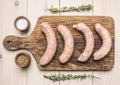 raw sausage frying Grilled lie on vintage cutting board with rosemary and spices on a white wooden rustic background, top view Royalty Free Stock Photo