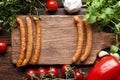 Raw sausage, vegetables and herbs on wooden board