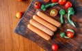 Raw sausage on a wooden cutting board with broccoli and tomatoes Royalty Free Stock Photo