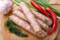 Raw sausages for frying on a wooden board with vegetables and dill. Royalty Free Stock Photo