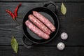 Raw Sausages with Herbs and Spices, on frying cast iron pan, on black wooden table background, top view flat lay Royalty Free Stock Photo