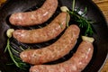 Raw sausages ready for preparation with rosemary, garlic and spices in cast iron grill frying pan Royalty Free Stock Photo