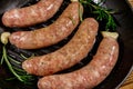 Raw sausages ready for preparation with rosemary, garlic and spices in cast iron grill frying pan Royalty Free Stock Photo