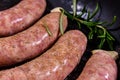 Raw sausages with rosemary twigs and garlic in a cast iron grill pan Royalty Free Stock Photo