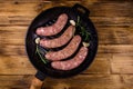 Raw sausages with rosemary twigs and garlic in a cast iron grill pan. Top view Royalty Free Stock Photo