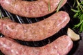 Raw sausages with rosemary twigs and garlic in a cast iron grill pan. Top view Royalty Free Stock Photo