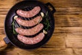 Raw sausages with rosemary twigs and garlic in a cast iron grill pan. Top view Royalty Free Stock Photo