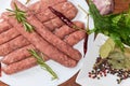 Raw sausages among spices and greens on dish close-up Royalty Free Stock Photo