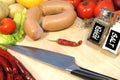 Raw Sausages, Vegetables and Big Chef's Knife on Wooden board Royalty Free Stock Photo