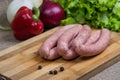Raw sausages with vegetables on wooden cutting board Royalty Free Stock Photo