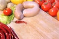 Raw Sausages and Vegetables on Wooden Cutting board Royalty Free Stock Photo