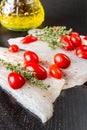 Raw sea bass fillets with cherry tomatoes on black wood Royalty Free Stock Photo