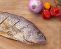 Raw seasoned fish on a wooden platter with some vegetables Royalty Free Stock Photo