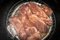 Raw seasoned pork ribs on grill inside barrel food smoker with herbs in tin foil to side