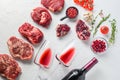 Raw set of alternative beef cuts Chuck eye roll, top blade, rump steak with red wine in glass and bottle, herbs and pomegranate. Royalty Free Stock Photo