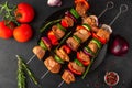 Raw shish kebab or shashlik. Marinated barbecue meat on skewers with vegetables and spices on black background