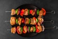 Raw shish kebab or shashlik. Marinated barbecue meat on skewers with vegetables and spices on black background. Top view