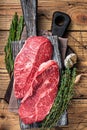 Raw Shoulder Top Blade beef meat steaks on a wooden butcher board with herbs. wooden background. Top View Royalty Free Stock Photo