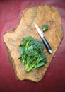 Raw sicilian broccoli and knife on wooden cutting board