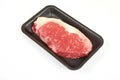 Raw sirloin beef steak in plastic packaging tray.