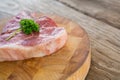 Raw Sirloin chop and corainder leaves on wooden tray against wooden background