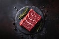 Raw sirloin steak with thyme, rosemary and spices. Top view. Flat lay top view on black stone cutting table