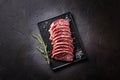 Raw sirloin steak with thyme, rosemary and spices. Top view. Flat lay top view on black stone cutting table