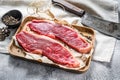 Raw sirloin steak on a wooden tray with a meat cleaver. Marble beef. Gray background. Top view Royalty Free Stock Photo