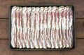 Raw sliced peppercorn bacon in baking sheet