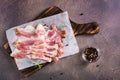 Raw smoked bacon and rosemary on a cutting board on the table. Hearty snack. Top view