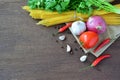 Raw spaghetti with tomato, garlic, onion and pepper, ingredients on brown wooden table. Royalty Free Stock Photo