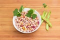 Raw speckled kidney beans in white bowl with bean stem