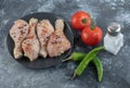 Raw spicy chicken drumstick with tomato, salt and pepper on grey background