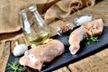 Raw spicy chicken legs ready for baking on a cutting board with a fresh rosemary, garlic, cumin, jug with oil, pepper and salt on Royalty Free Stock Photo