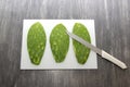 Raw spineless fresh green Mexican nopales on a chopping board and knife ready to cook