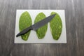 Raw spineless fresh green Mexican nopales on a chopping board and knife ready to cook